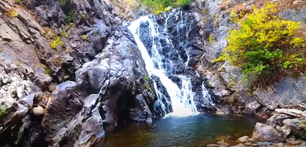 A waterfall surrounded by large rocks and a few trees