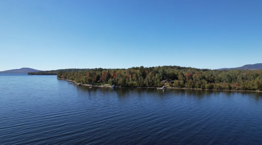 lake and land with trees near it, hills behind it