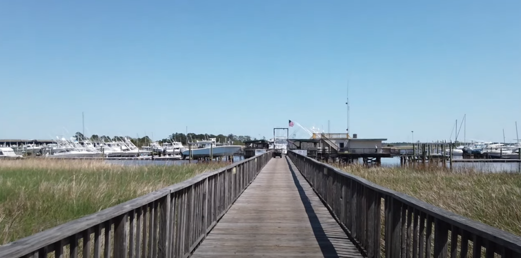 bridge over a lake with boats and grass beside