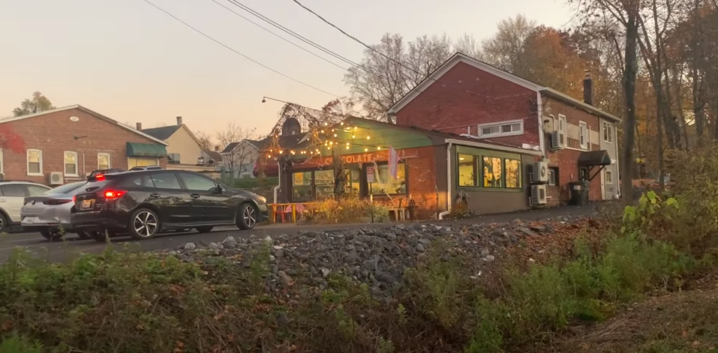 A cafe with a parked cars in front